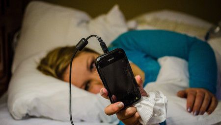 Frau die im Bett Liegt und auf ihr Handy schaut