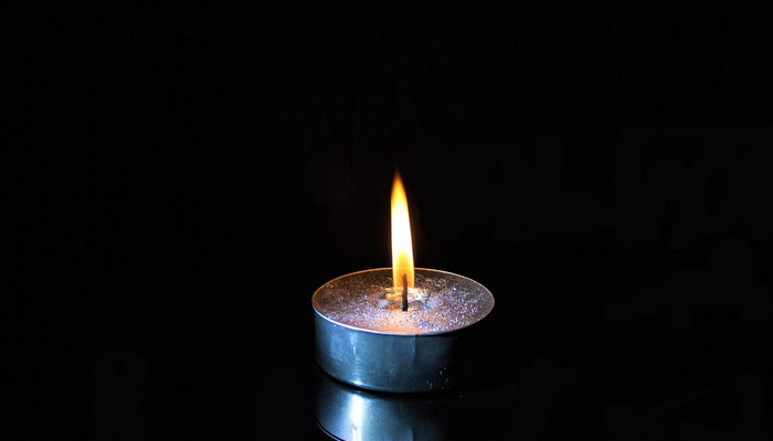 Angezündete Kerze mit schwarzem Hintergrund