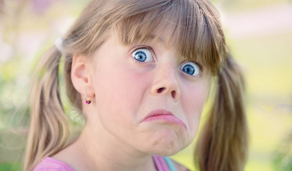 enfant qui fait une grimace et regarde vers la caméra