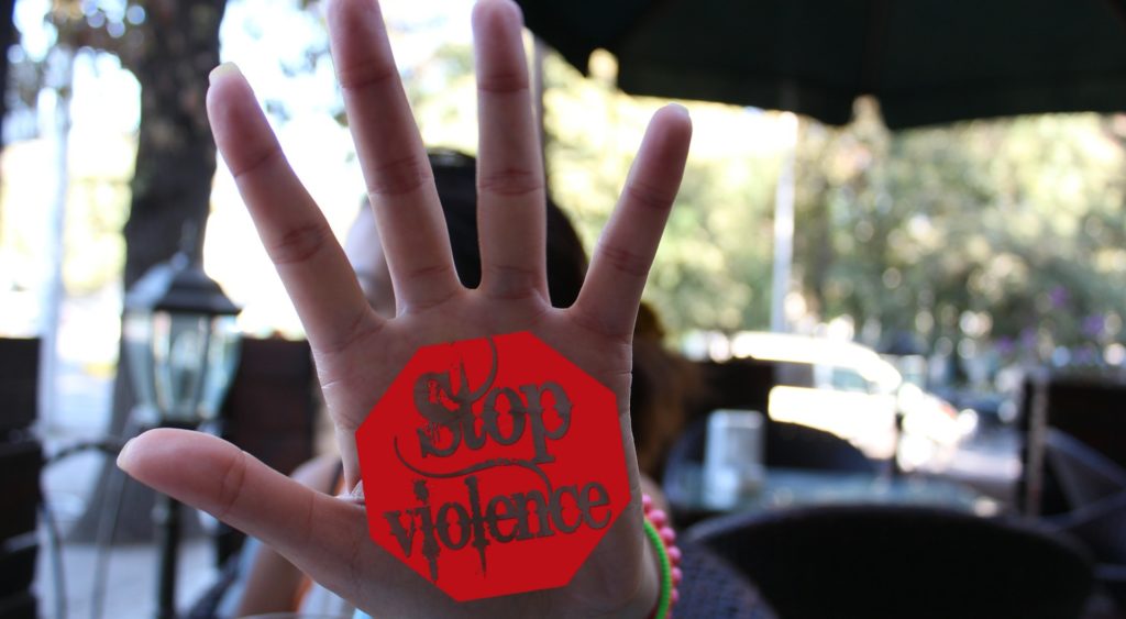 Une personne tenant sa main vers l'appareil. Sur la main il est écrit dessus "Stop violence"