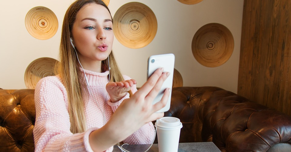 jeune fille portant des écouteurs se prend en selfie avec son smartphone