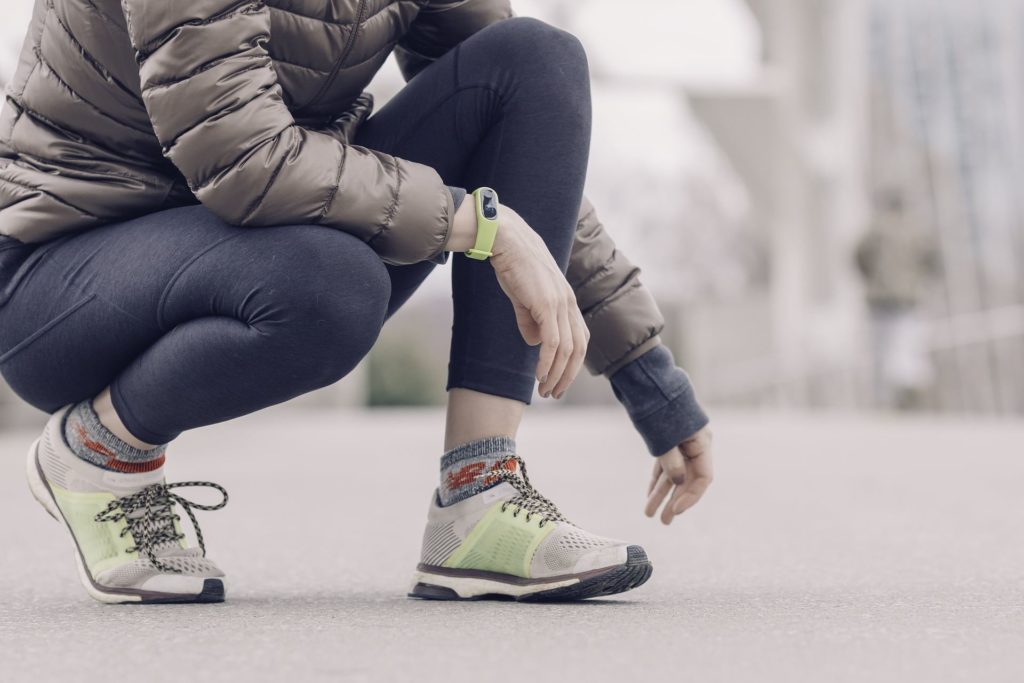 Frau im Lauf-outfit mit einer Fitnessuhr