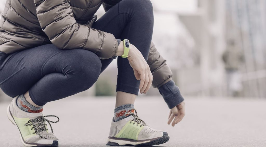 Vue coupée d'une personne accroupie en tenue de sport avec une montre connectée au poignet