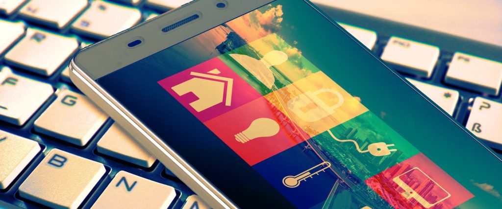 Smartphone posé sur un clavier d'ordinateur avec une application de domotique à l'écran