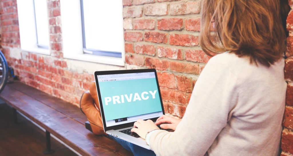 Femme avec un ordinateur sur les genoux qui regarde un écran où est écrit "privacy"
