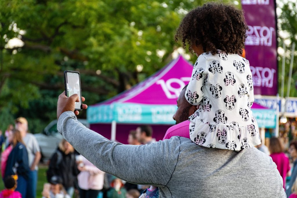 Mann mit Kind auf den Schultern die ein Selfie machen