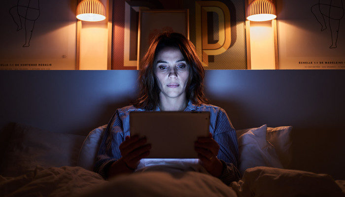 Eine Frau Abends im Bett mit einem Tablet in der Hand