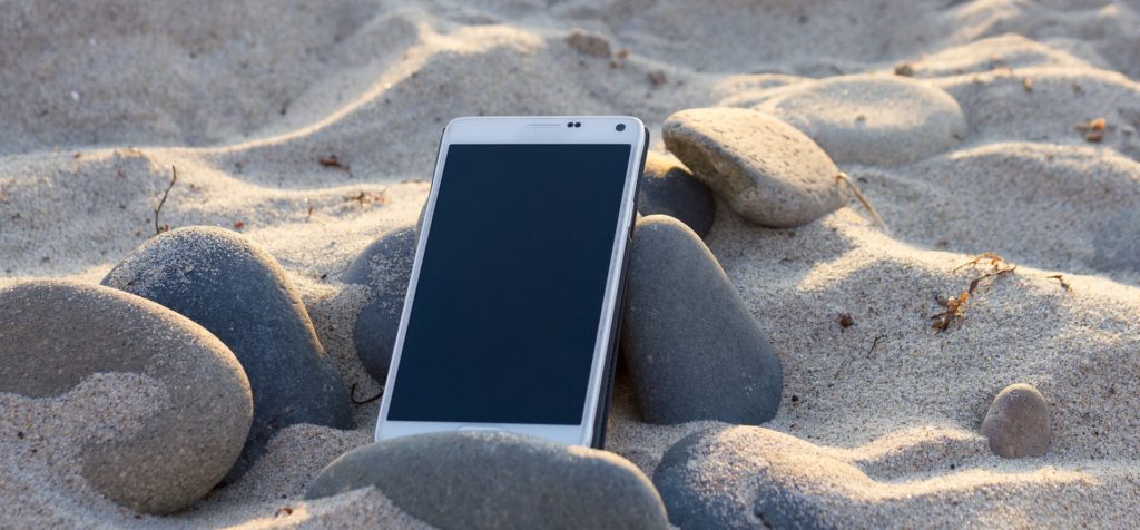 Un smartphone posé dans le sable sur une plage