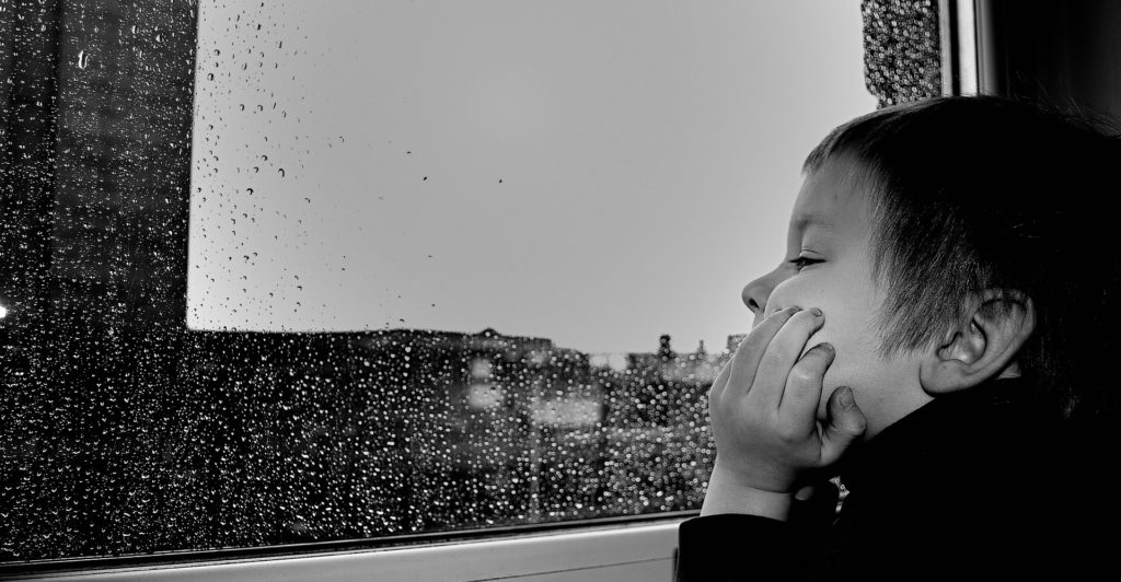 Photo d'un enfant qui regarde par la fenêtre un jour de pluie