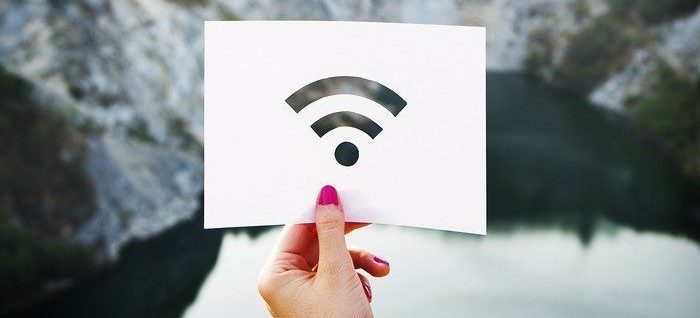 Une main tenant un papier avec le signal du wifi avec des montagnes en arrière plan