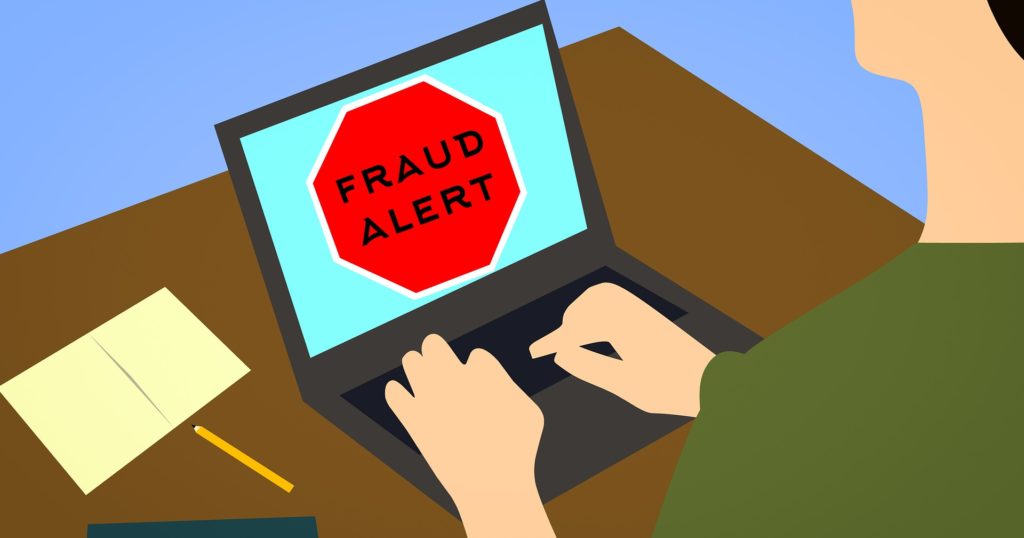 Illustration d'une personne assise devant un ordimateur portable. L'écran affiche le message "FRAUD ALERT"