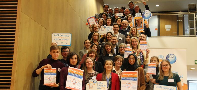 Gruppe von Jugendbotschafter die zusammen in einer Treppe posieren und das Safer Internet Day Logo in die Kamera halten