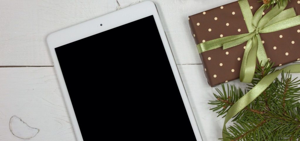 tech-gift Photo d'un iPad posé sur une table à côté d'un cadeau de Noël