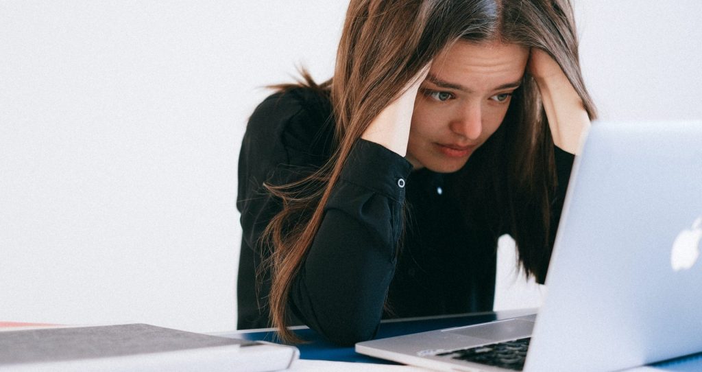 Jeune femme regardant son ordinateur de façon inquiète