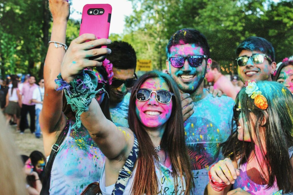 Jugendliche mit Farbe im Gesicht lächeln und machein ein Selfie