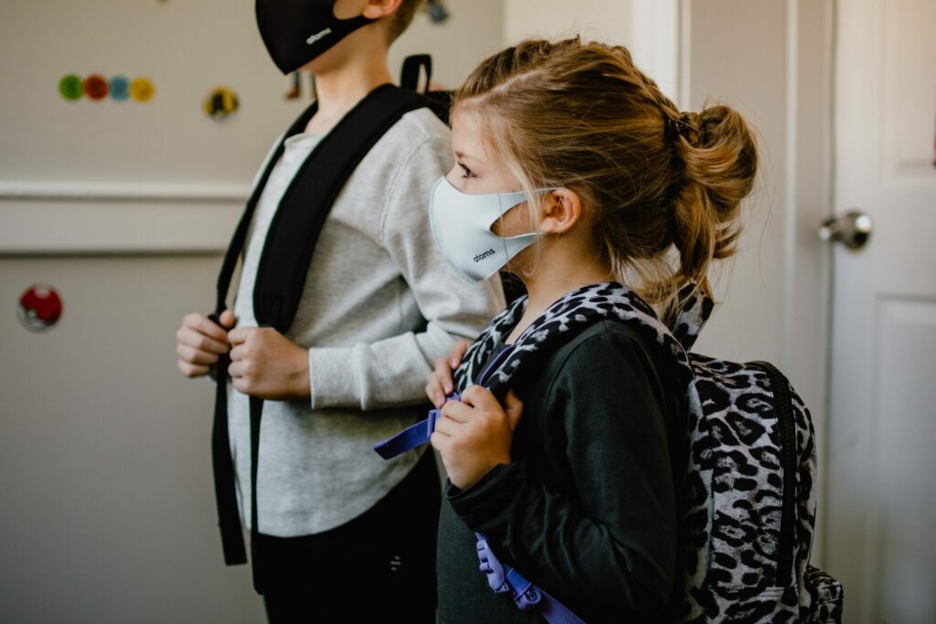 Petit garçon et petite fille avec masque et cartable